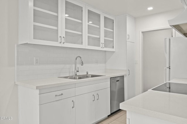 kitchen with a sink, backsplash, freestanding refrigerator, white cabinetry, and stainless steel dishwasher