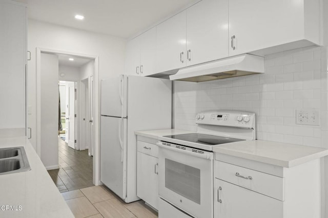 kitchen with white appliances, light countertops, under cabinet range hood, white cabinetry, and tasteful backsplash