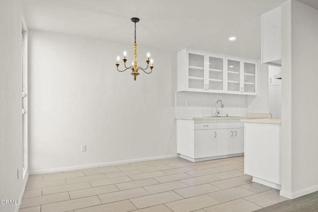 kitchen featuring a sink, tasteful backsplash, white cabinetry, light countertops, and wood tiled floor