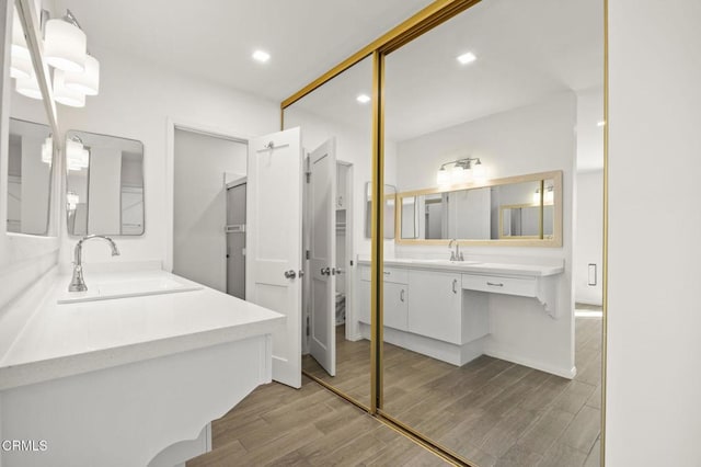 full bathroom featuring recessed lighting, wood finished floors, two vanities, and a sink