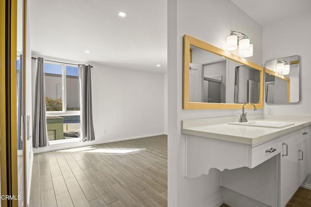 bathroom featuring recessed lighting, baseboards, wood finished floors, and vanity