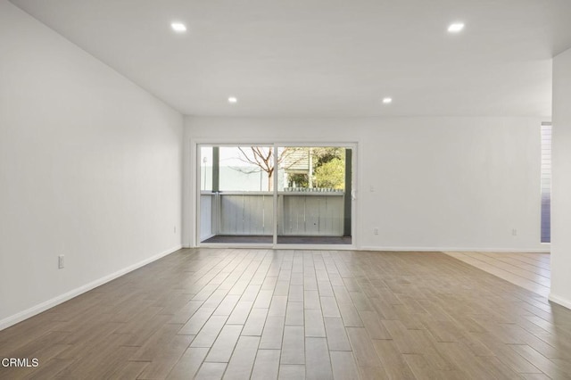 spare room featuring recessed lighting, wood finished floors, and baseboards