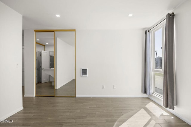 unfurnished room featuring recessed lighting, wood finished floors, and baseboards