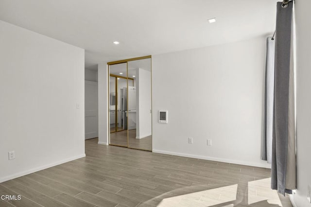 empty room featuring recessed lighting, wood finished floors, and baseboards