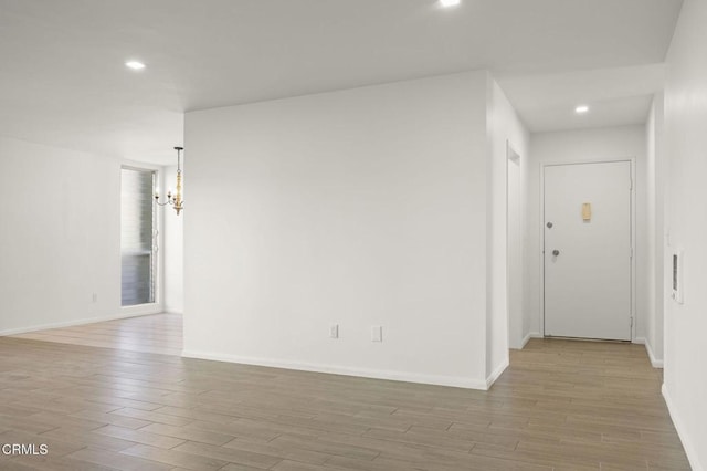 empty room featuring baseboards, an inviting chandelier, and wood finished floors