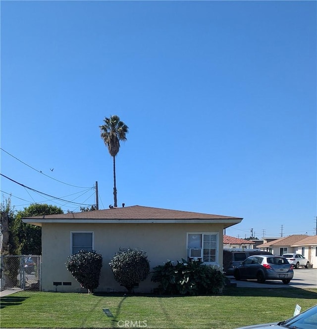 view of property exterior featuring a gate, stucco siding, a yard, and fence