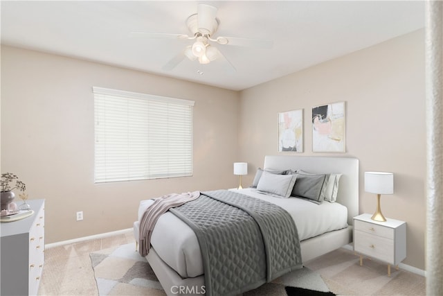 bedroom featuring light colored carpet, baseboards, and ceiling fan