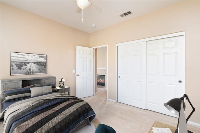 bedroom with visible vents, light colored carpet, a closet, and a ceiling fan