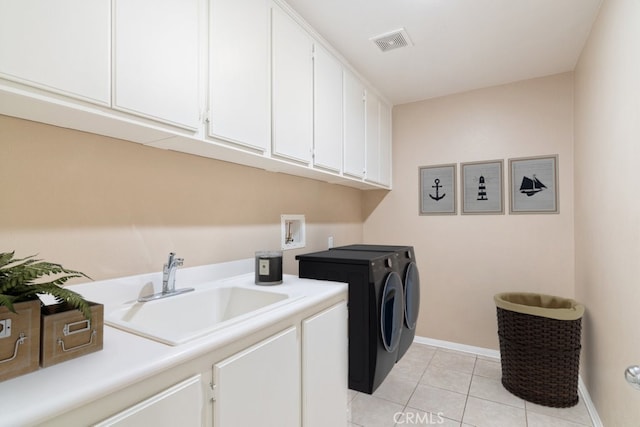 washroom with light tile patterned floors, visible vents, washing machine and clothes dryer, cabinet space, and a sink