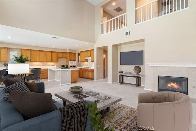 living area featuring a fireplace, baseboards, visible vents, and light colored carpet