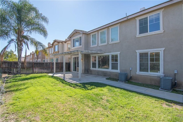 back of house featuring stucco siding, cooling unit, a lawn, and fence