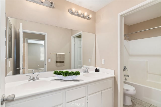 bathroom with tile patterned floors, double vanity, toilet, and a sink