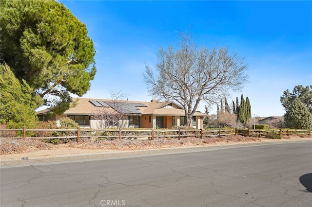 view of front facade with a fenced front yard and roof mounted solar panels