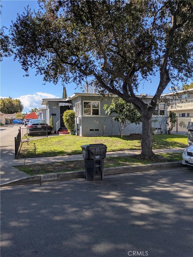 view of front of property with entry steps, a front yard, and fence