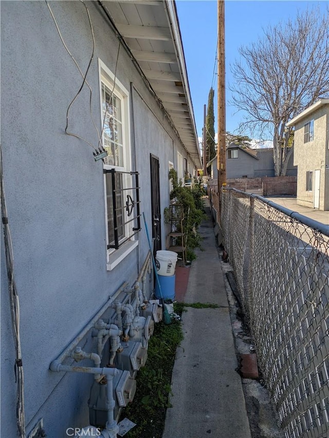 view of side of property with stucco siding and fence