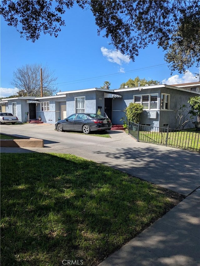 view of front of property featuring driveway, a front lawn, and fence