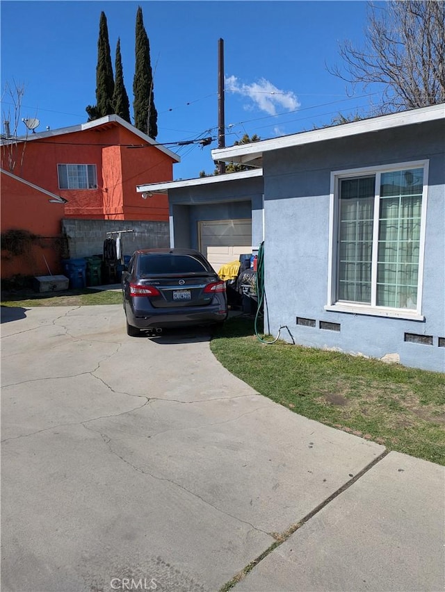 view of side of property featuring stucco siding, a garage, and driveway