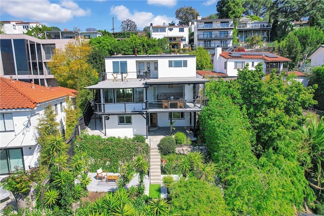 back of property with a residential view, stucco siding, and a balcony