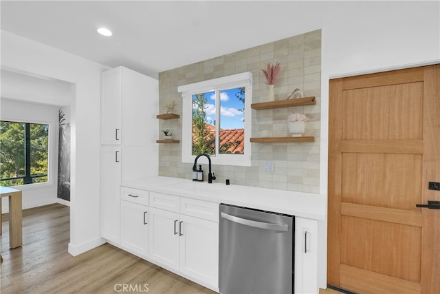 kitchen featuring open shelves, a sink, light countertops, dishwasher, and tasteful backsplash