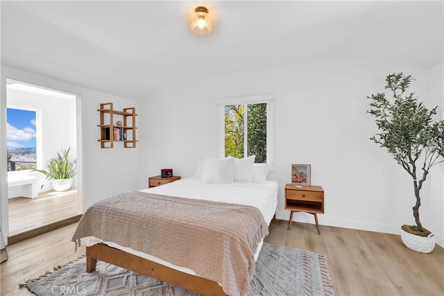 bedroom featuring multiple windows, lofted ceiling, light wood-style floors, and baseboards