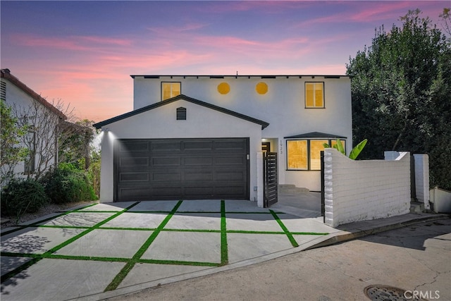 view of front of house with concrete driveway, fence, a garage, and stucco siding