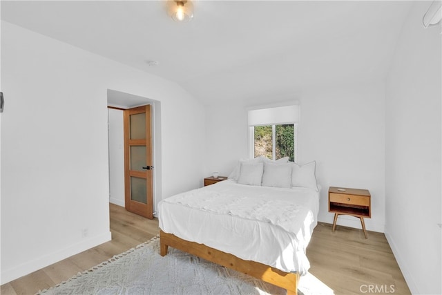 bedroom with baseboards, light wood-style floors, and vaulted ceiling