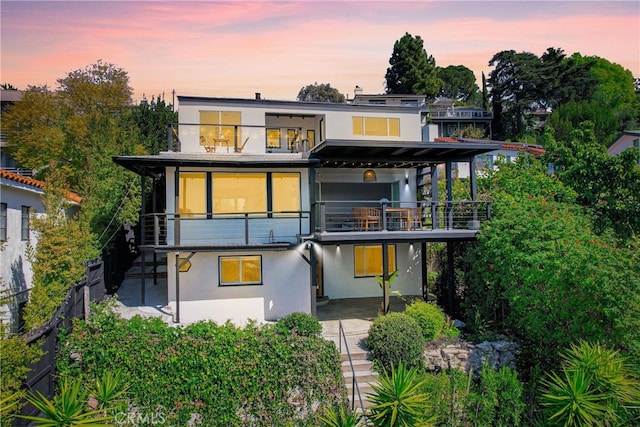 back of property with a balcony and stucco siding