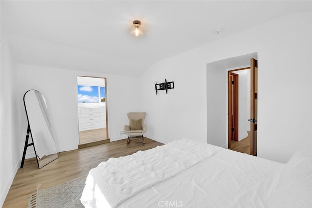 bedroom with baseboards, wood finished floors, and vaulted ceiling