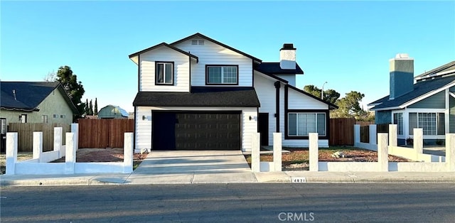 view of front of home featuring concrete driveway, fence, a garage, and a chimney