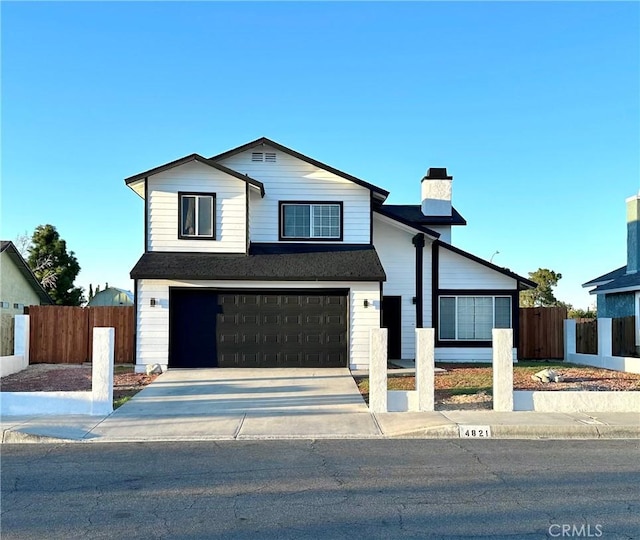 view of front of home with an attached garage, fence, driveway, and a chimney