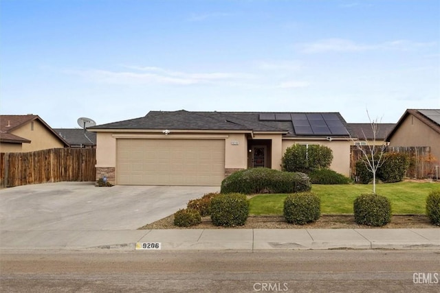 single story home with stucco siding, roof mounted solar panels, an attached garage, and a front yard