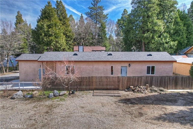 back of house featuring fence and stucco siding