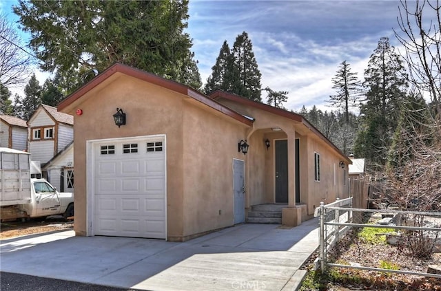 view of front facade with concrete driveway, fence, and stucco siding