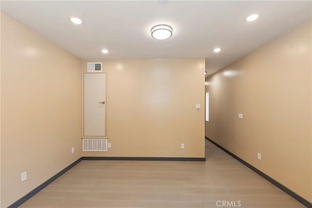 empty room featuring visible vents, light wood-type flooring, and baseboards