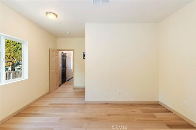 spare room featuring visible vents, light wood-type flooring, and baseboards