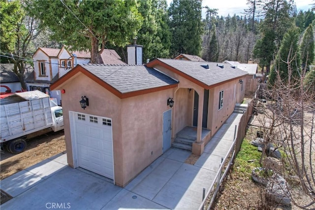 view of front of home featuring stucco siding, driveway, a chimney, and roof with shingles