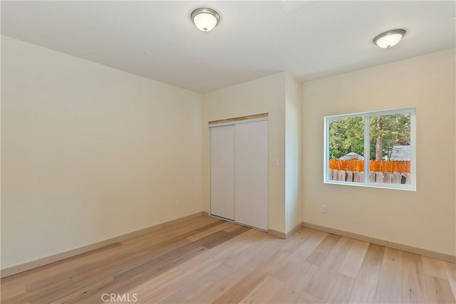 unfurnished bedroom with baseboards, a closet, and light wood finished floors