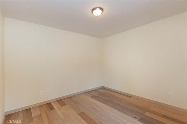 unfurnished room with baseboards and light wood-style floors