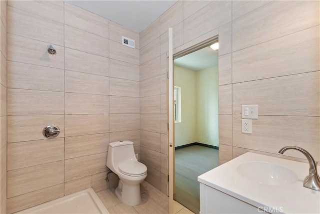 bathroom featuring visible vents, tiled shower, toilet, and tile walls