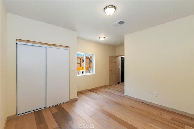 unfurnished bedroom with visible vents, baseboards, a closet, and light wood-style flooring