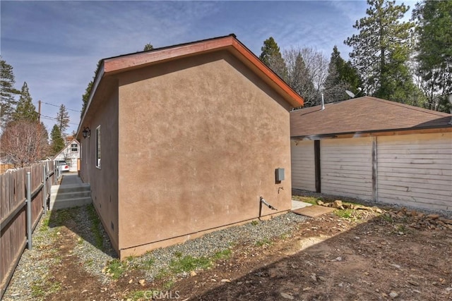 view of side of home featuring stucco siding and fence