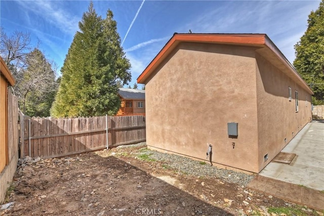 view of side of home with fence and stucco siding