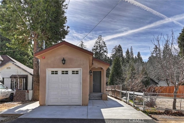 view of front of home featuring an attached garage, fence, and stucco siding