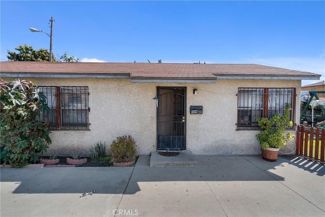 view of front of property with a patio area, stucco siding, and fence