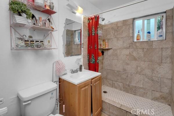 bathroom featuring vanity, toilet, and a tile shower