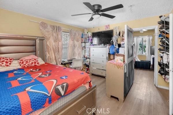 bedroom with a textured ceiling, ceiling fan, and wood finished floors