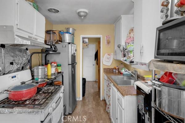 kitchen with a sink, light wood-type flooring, white cabinetry, and stainless steel appliances