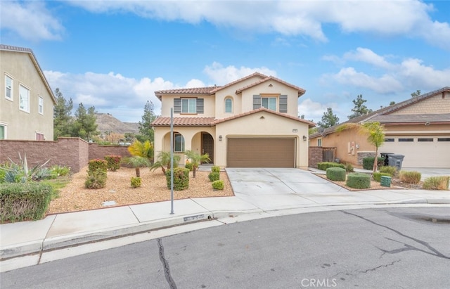 mediterranean / spanish home featuring fence, an attached garage, stucco siding, concrete driveway, and a tiled roof