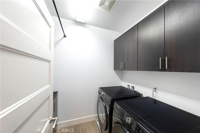 washroom with visible vents, baseboards, washer and dryer, light wood-style floors, and cabinet space