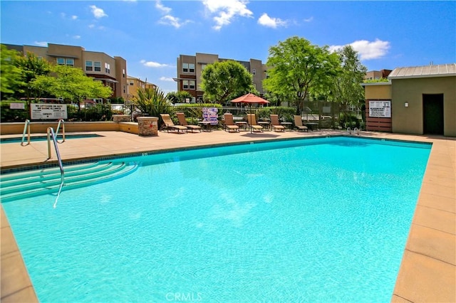 community pool with a patio area and fence